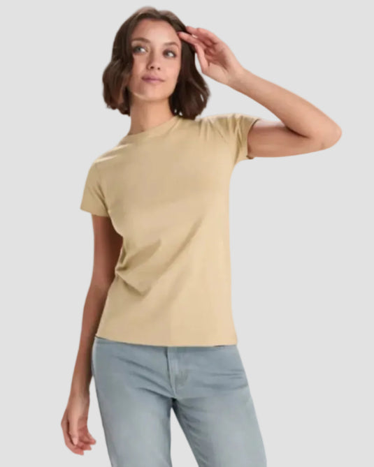 Woman wearing a beige t-shirt and light blue jeans on a white background