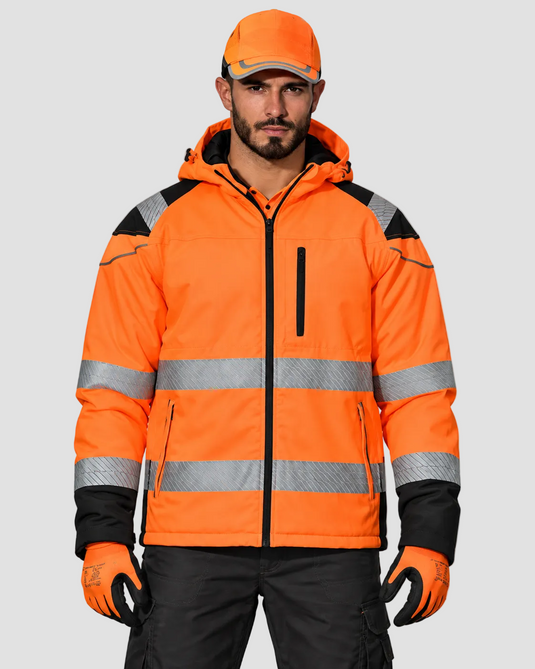 A man wearing a bright orange high-visibility work jacket with reflective silver stripes, black shoulder panels, and black gloves, paired with an orange cap and dark cargo pants, against a light gray studio background.