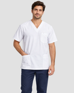 A man wearing a white V-neck scrub top with a chest pocket and two lower front pockets, paired with navy pants, against a light gray studio background.