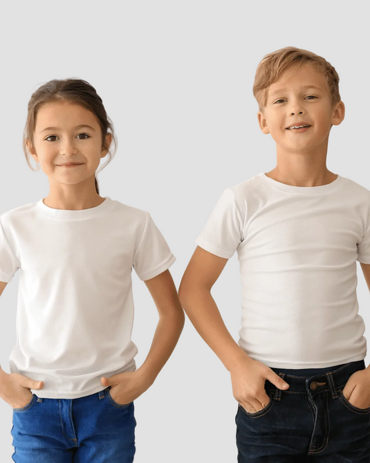 Two children, a girl on the left in a white t-shirt and blue jeans, and a boy on the right in a white t-shirt and dark pants, standing side by side with hands in pockets.