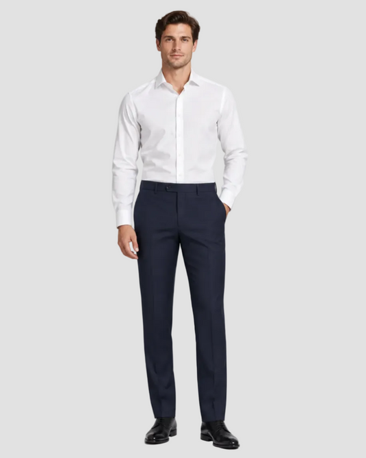 A man modeling a white long-sleeve dress shirt and navy blue dress pants with black dress shoes, standing against a light gray studio background.