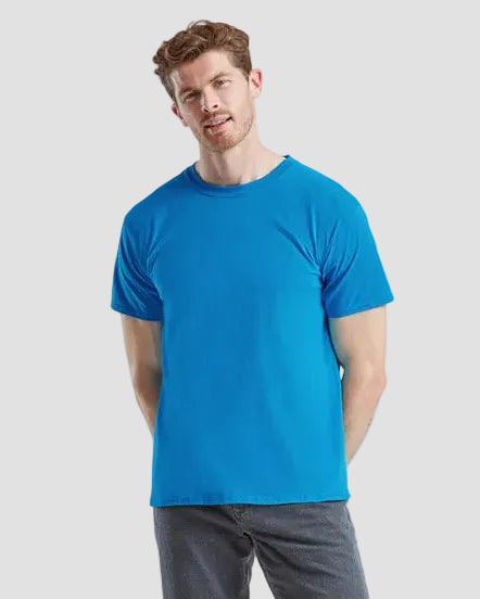 Man wearing a blue t-shirt and gray pants on a light gray background