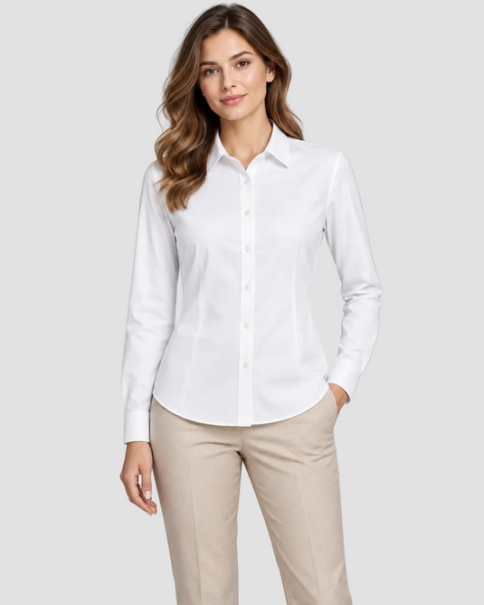 A woman modeling a white long-sleeve button-down shirt with beige trousers, standing against a solid light gray studio background.