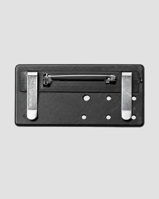 A black rectangular metal accessory with two silver metal clips or fasteners, photographed from above on a light gray background.